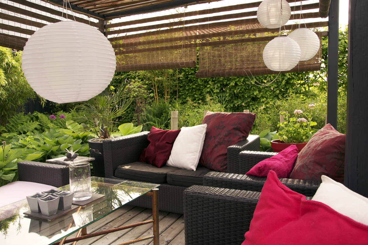 Pergola with lamps, patio furniture, and sun shades for privacy.
