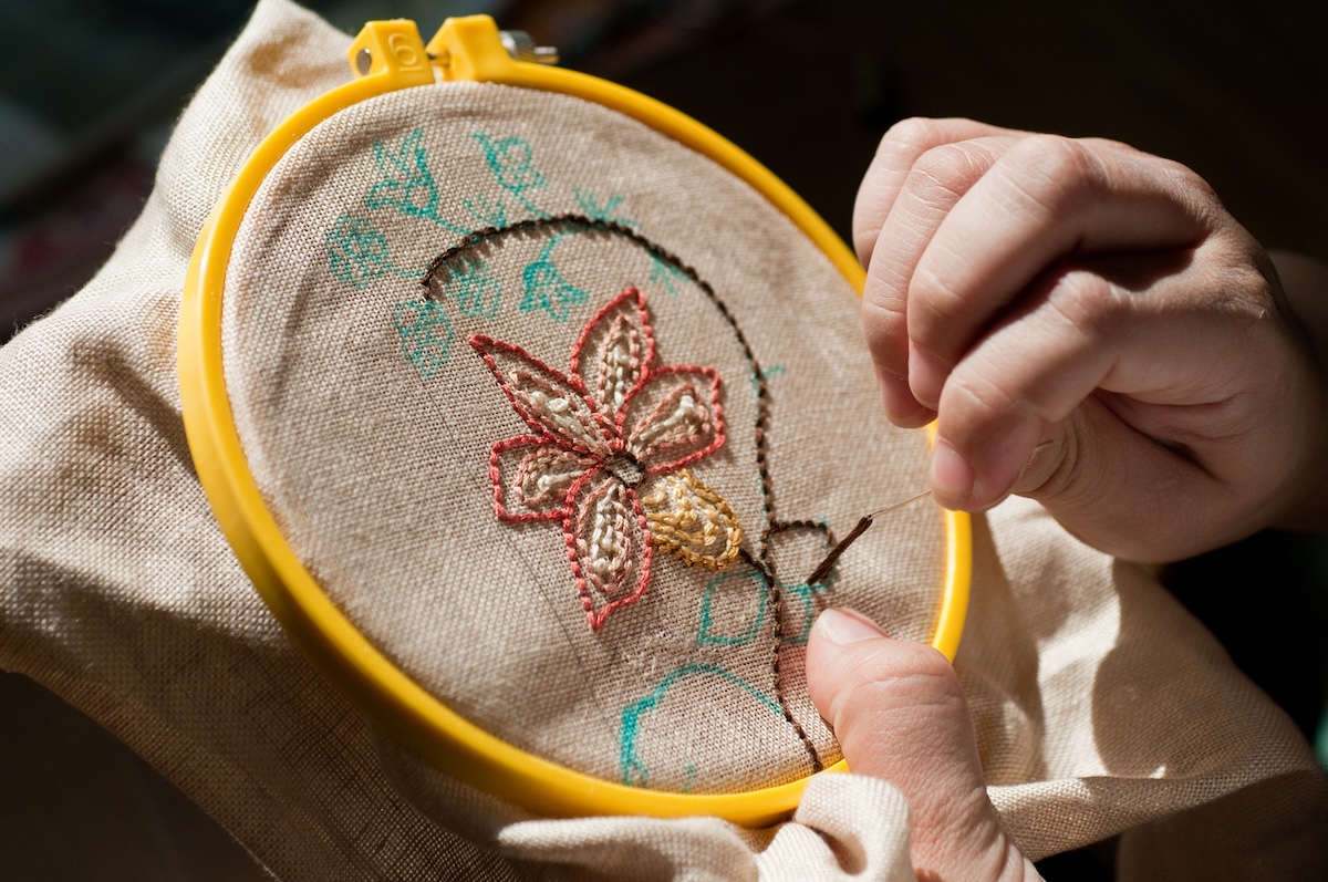 A person embroidering a flower on fabric.