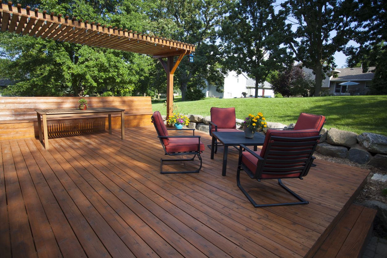 Deck with red patio furniture and pergola covering a picnic table.