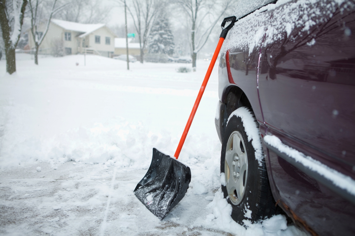 Snow shovel leaning on car.