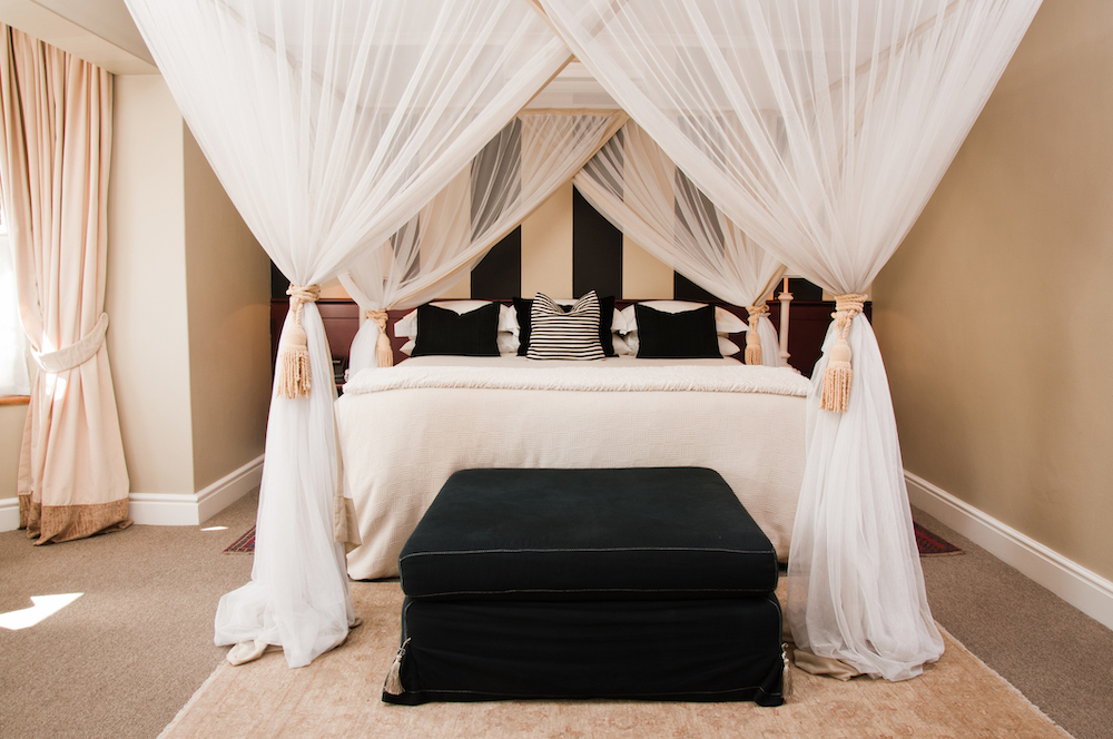 Sheer-curtains-create-a-canopy-around-a-black-and-white-bed.