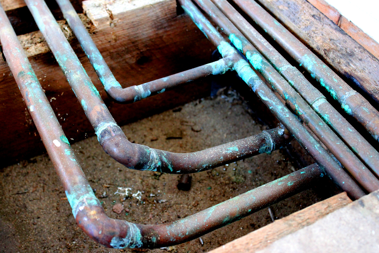 Close-up photo of old copper under floor central heating radiator pipes and hot water pipes - flow, return, hot and cold.