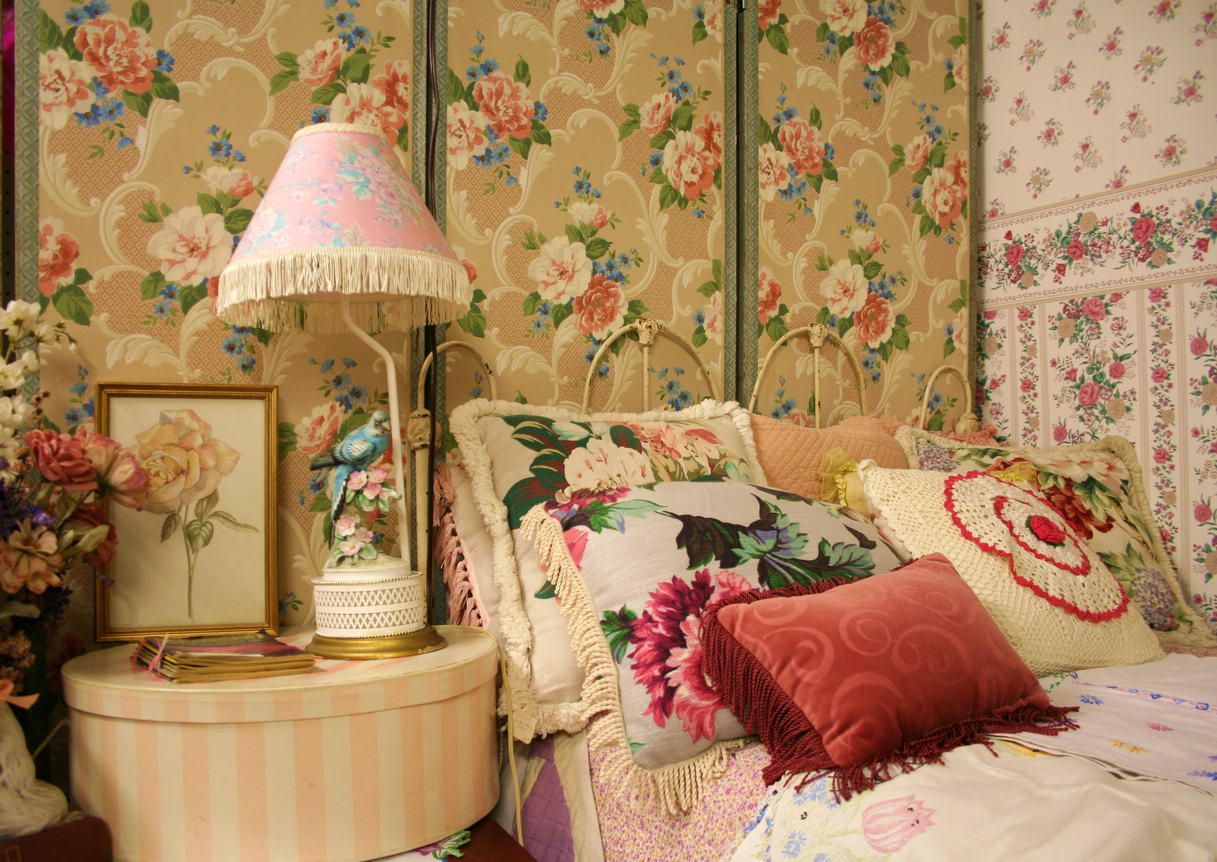 A-mix-of-floral-chintz-fabrics-cover-pillows-walls-and-other-surfaces-in-a-bedroom-corner.