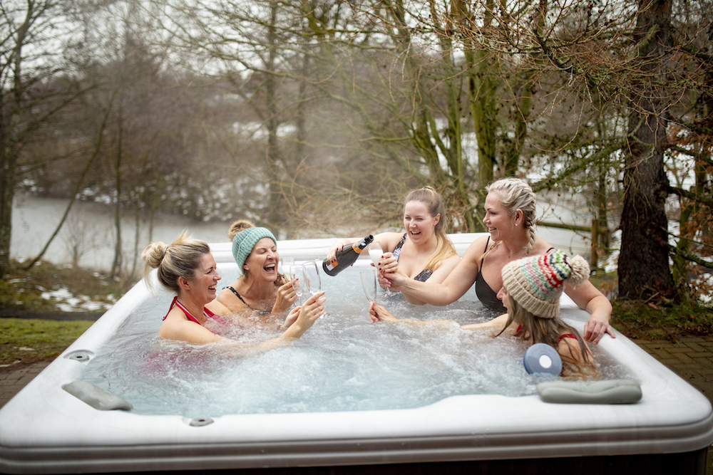 Five-women-are-laughing-and-sharing-champagne-in-a-hot-tub-in-the-winter.