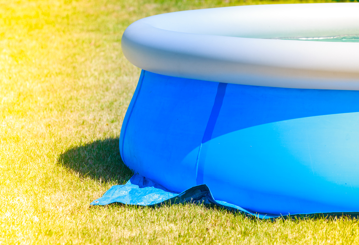 Blue and white round inflatable pool on yellow grass.
