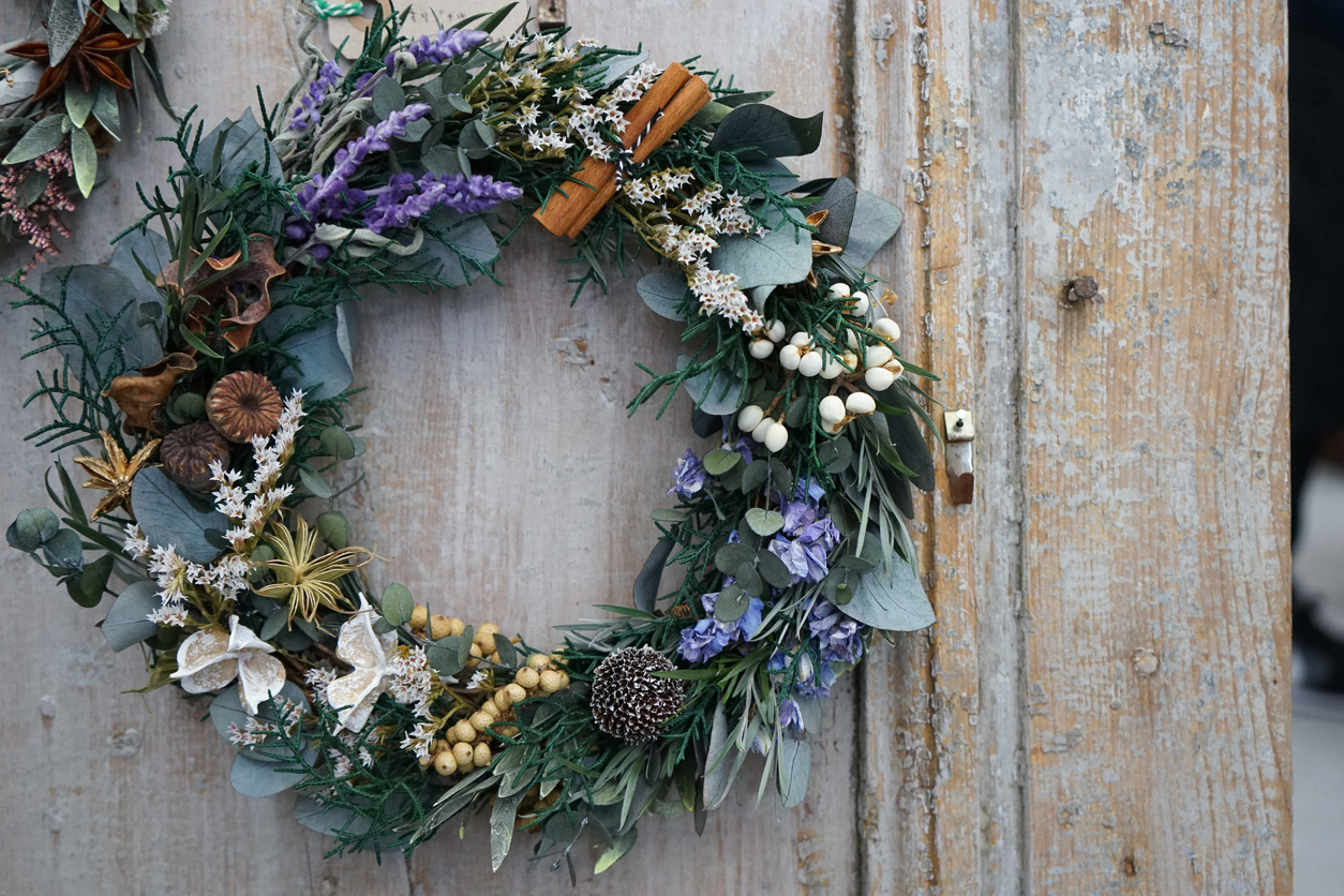 Winter wreath with lavender and cinnamon sticks, and flowers on a weathered door.