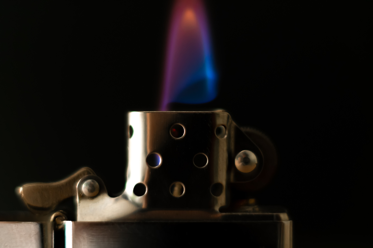 Close view of a flame burning on a zippo lighter with a black background.