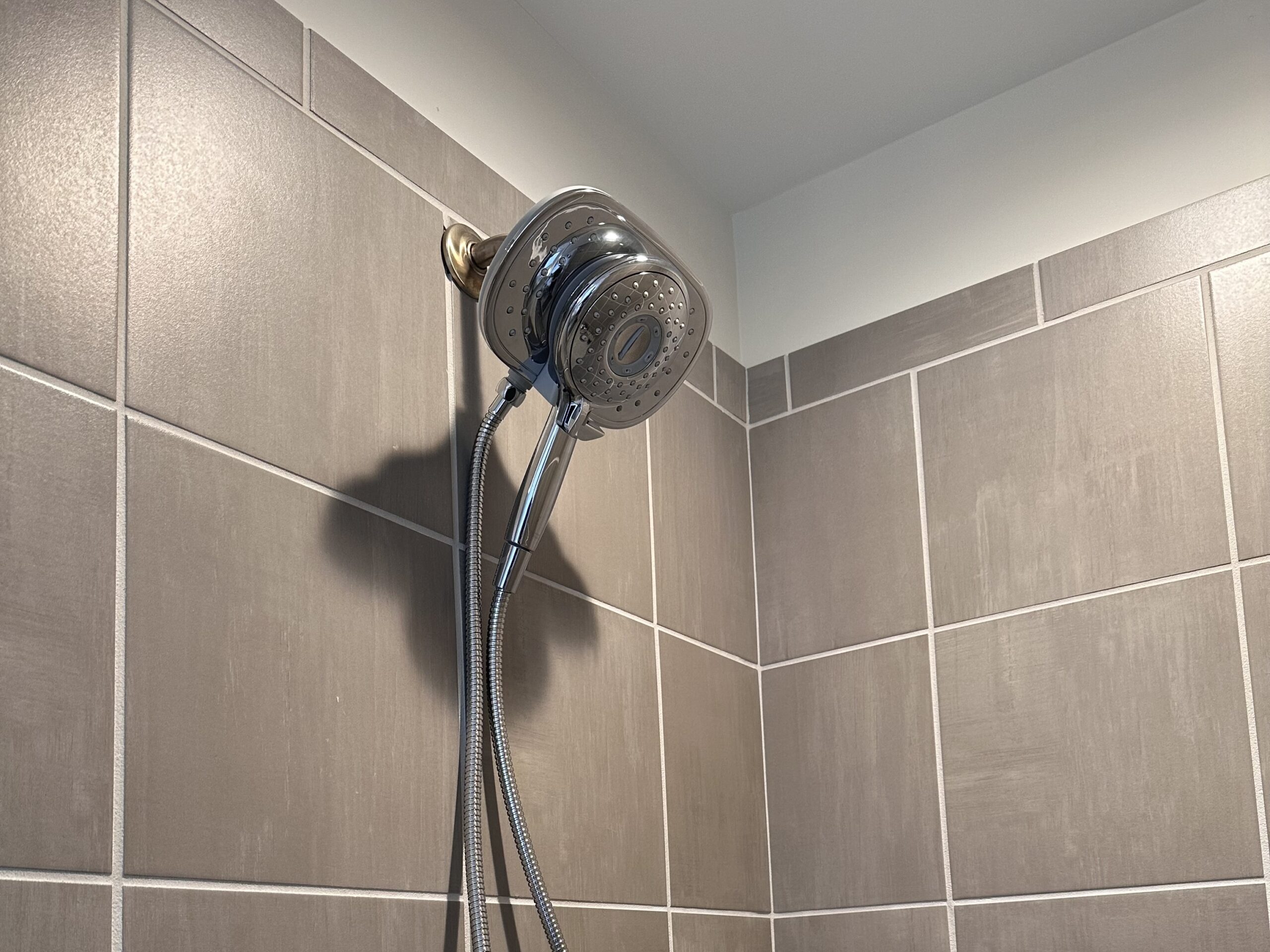 Chrome American Standard Spectra Plus Duo Shower Head mounted on taupe tile wall