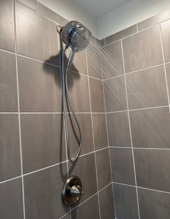 Chrome American Standard Spectra Plus Duo Shower Head mounted on square taupe tile wall