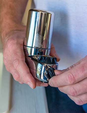 A person holding the Brita Complete water faucet filter while twisting its on/off lever.