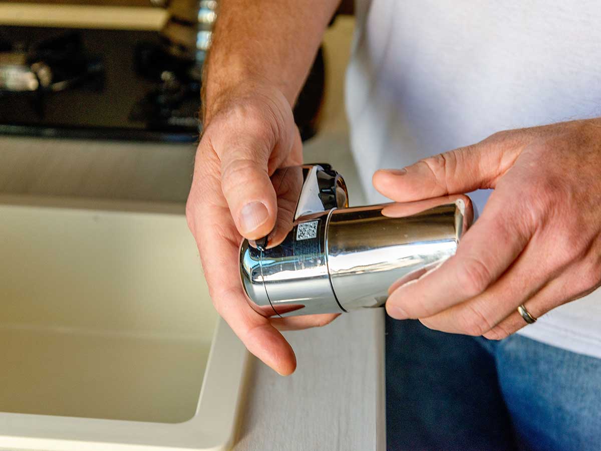 A person holding the small Brita Complete water faucet filter in their hands prior to installation.