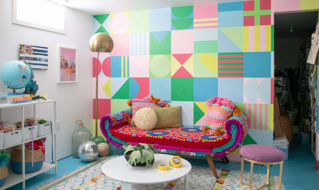 A colorful graphic mural is painted in pastel colors in an eclectic room.