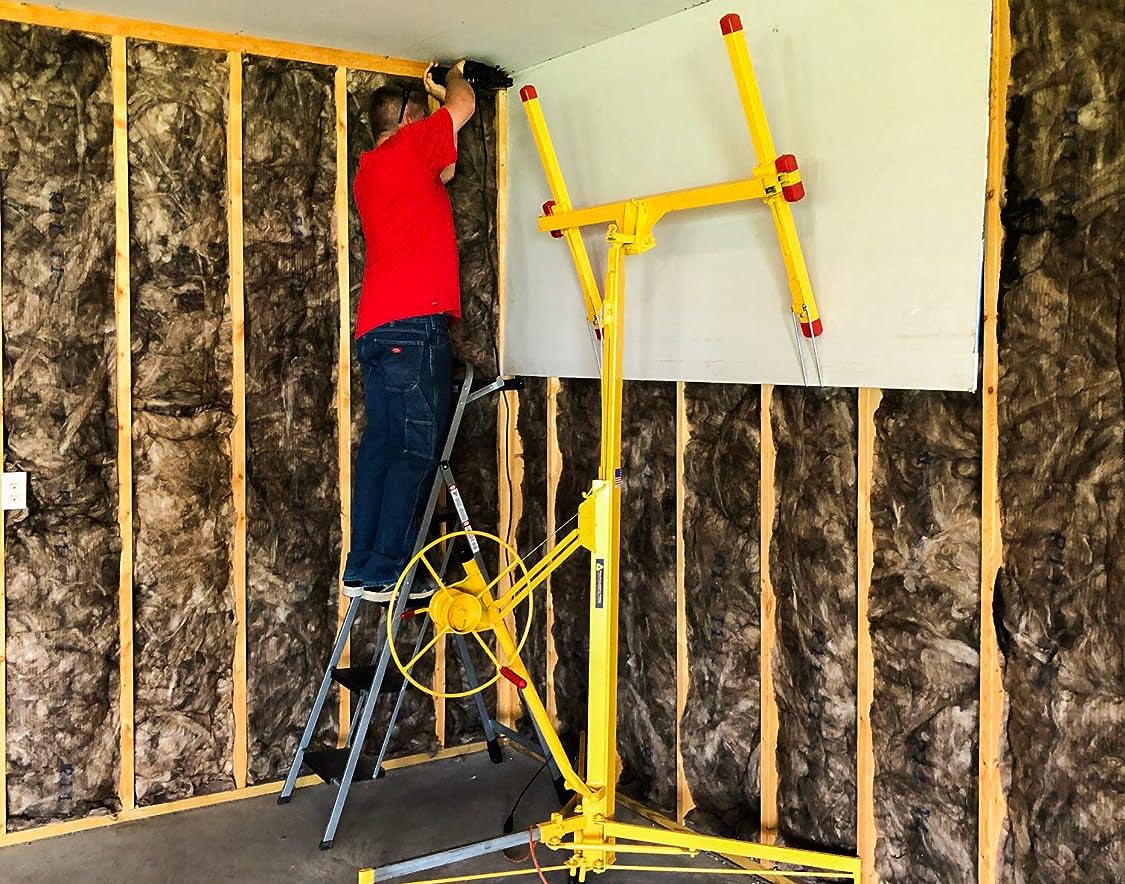 A person using the best drywall lift to install a large panel of drywall in a room being built.
