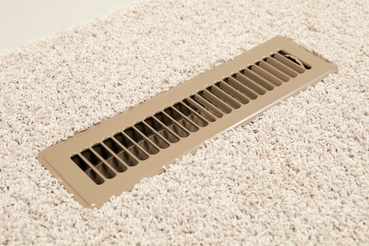 Air vent in a floor with beige carpeting.