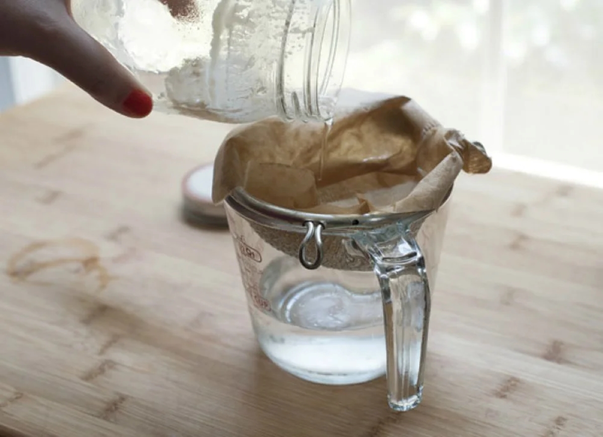 Using coffee filter to strain liquid from mason jar.