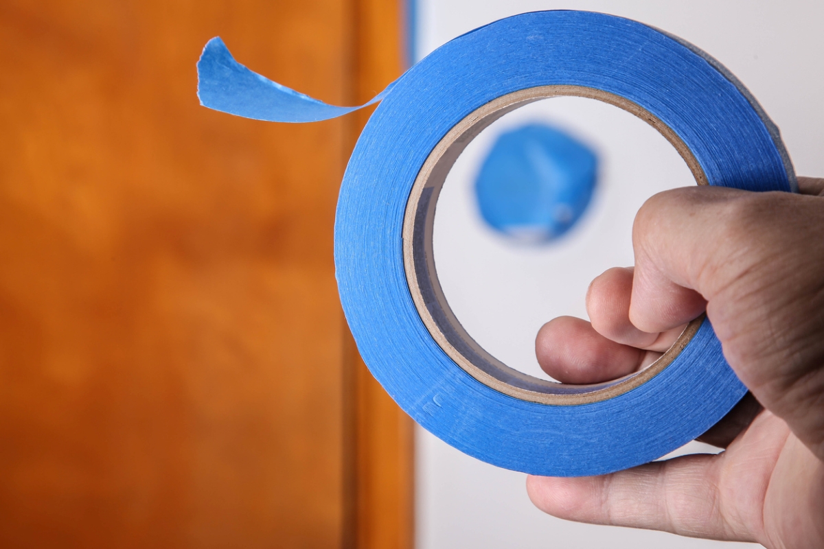Person holding roll of blue tape.