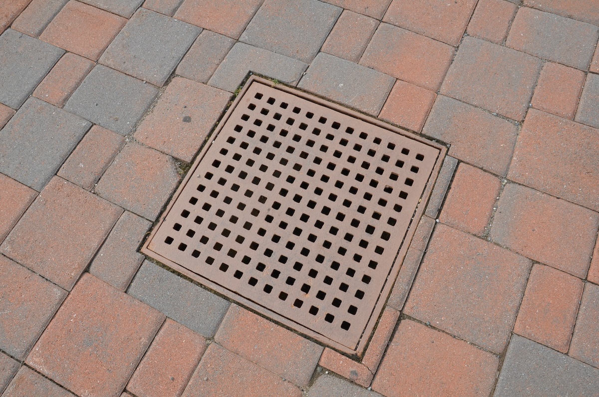 A catch basin installed in a residential brick driveway.