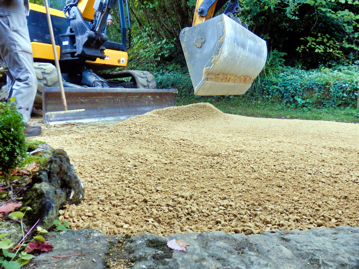 Regrading a home driveway with yellow front loader tractor.