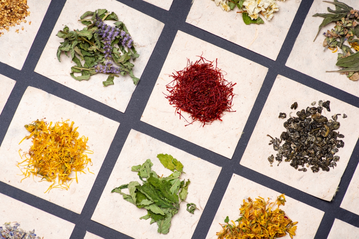 Different colorful herbs laid on pieces of paper.