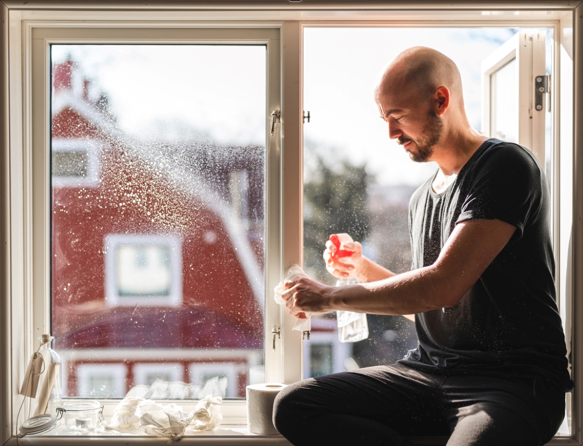 Man cleaning window with paper.