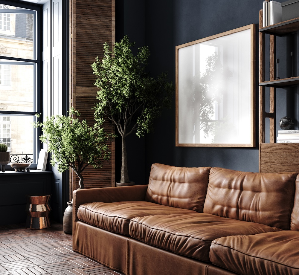 Cozy living room with brown leather sofa, charcoal walls, house plants, and wooden window shades.