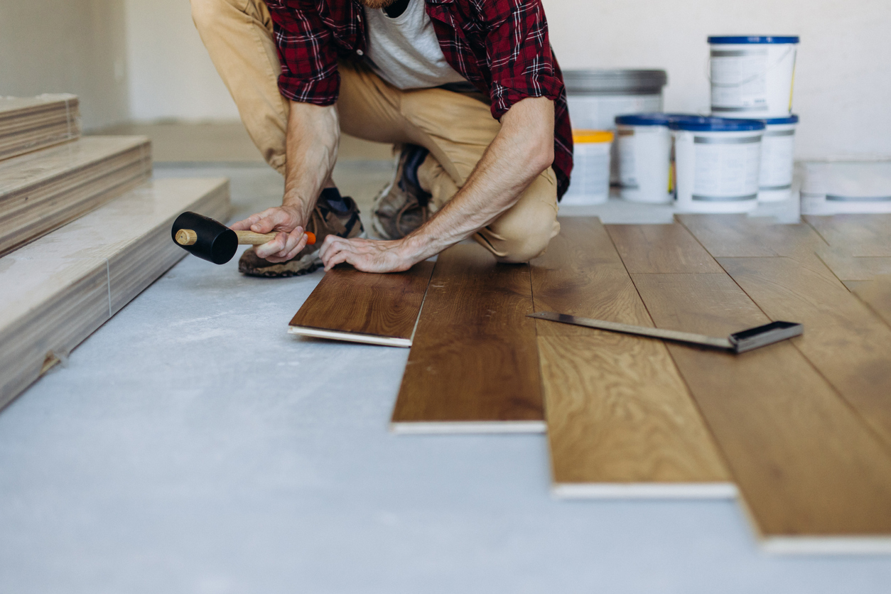 A-person-uses-a-mallet-to-repair-vinyl-plank-flooring.