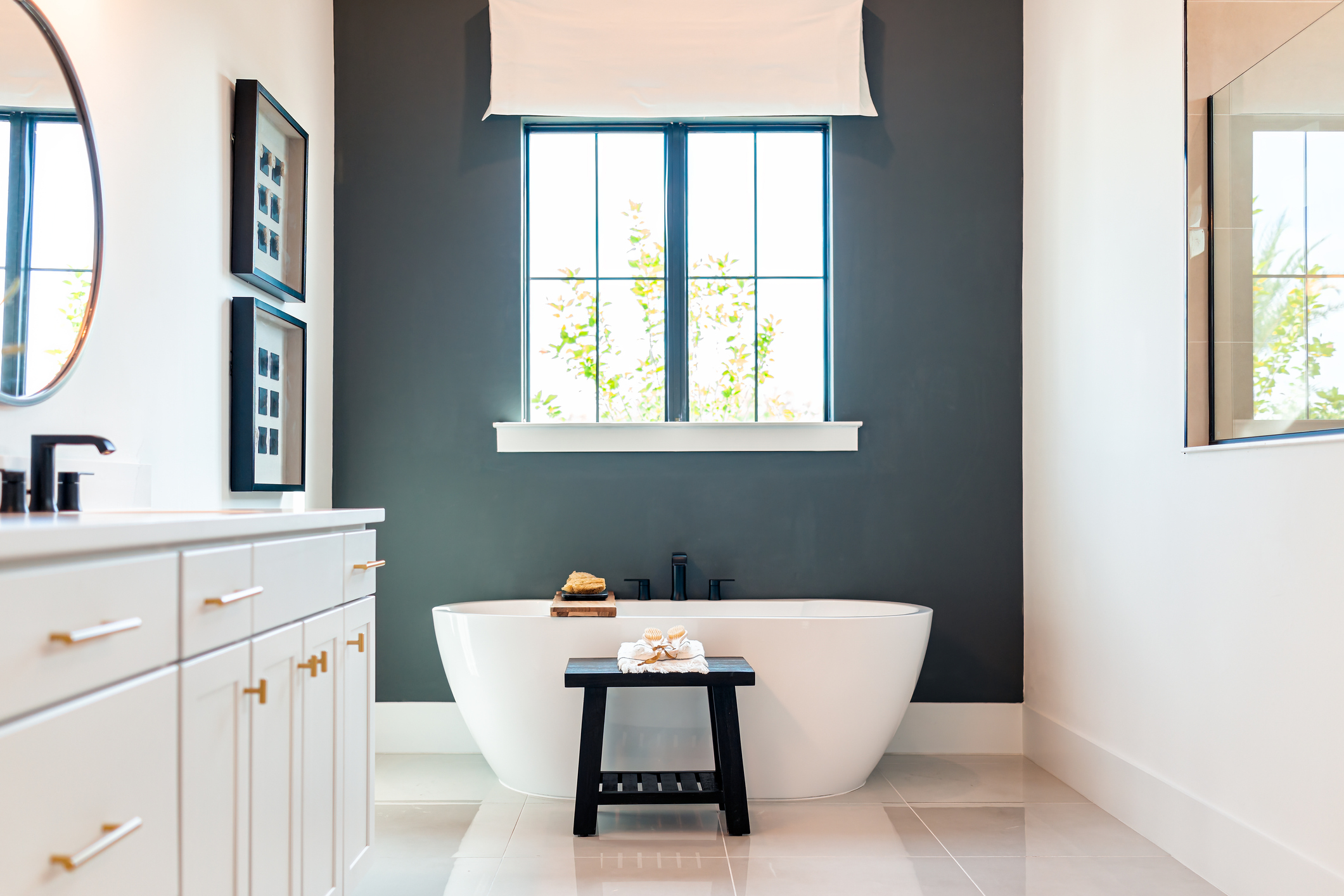 White, modern bathroom with dark blue accent wall behind a tub.