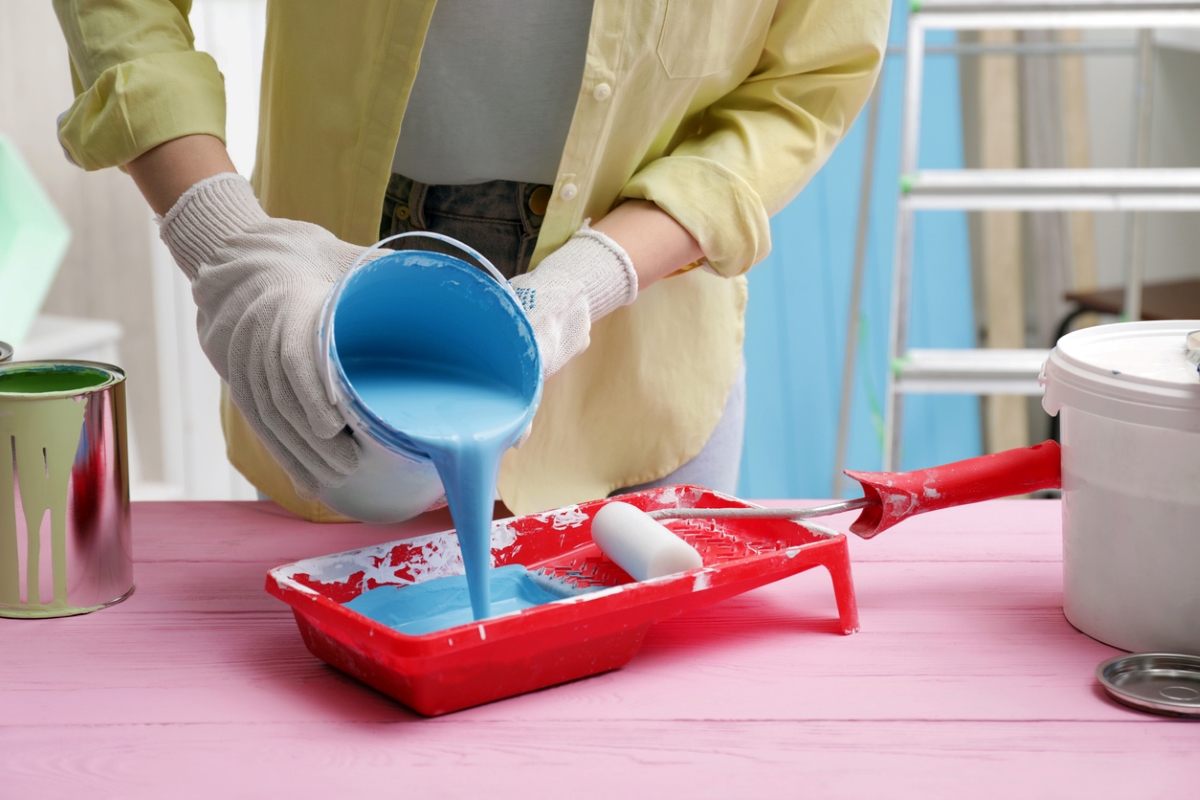 Person pouring blue paint in tray.