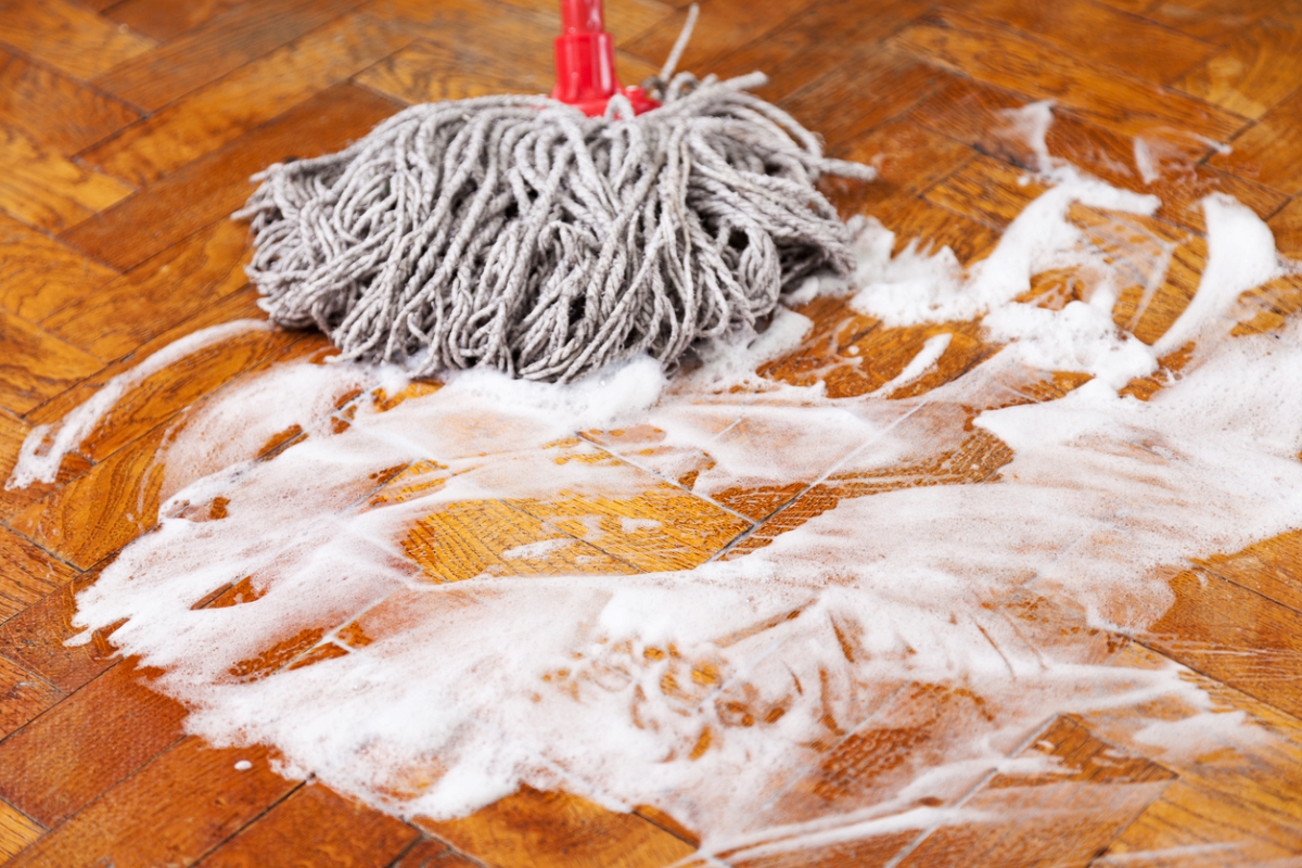 Mop used to clean wooden floor with soapy cleaner.
