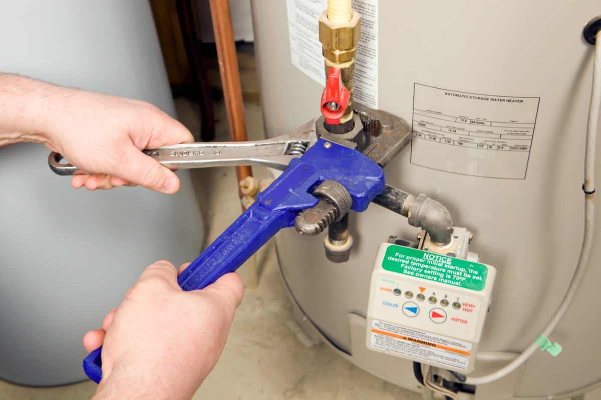 Person using wrench on water heater.