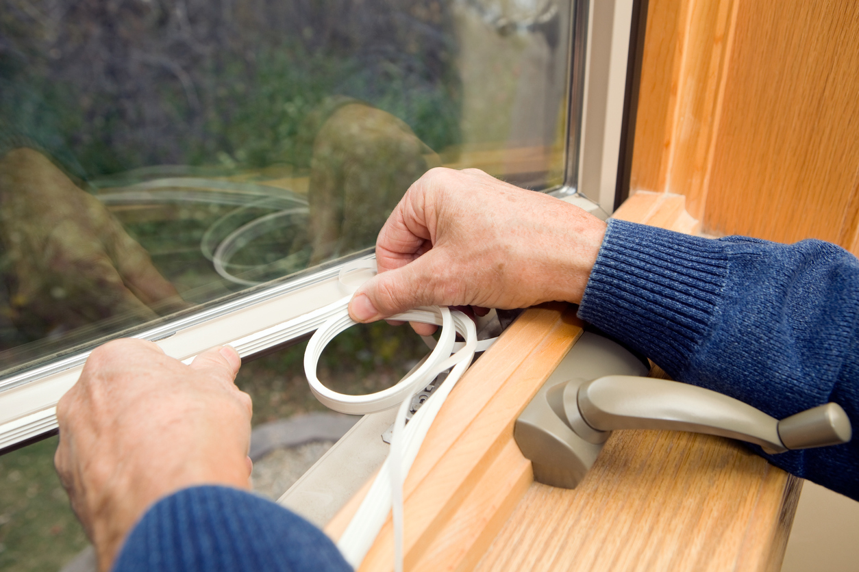 Hands-apply-weatherstripping-to-an-open-window.
