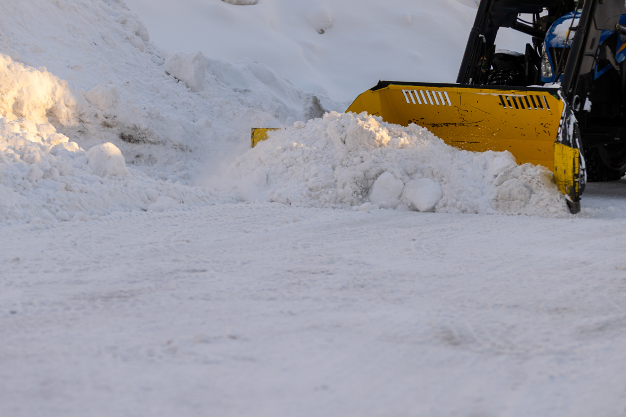 Close-up of yellow snowblower near snowbank.