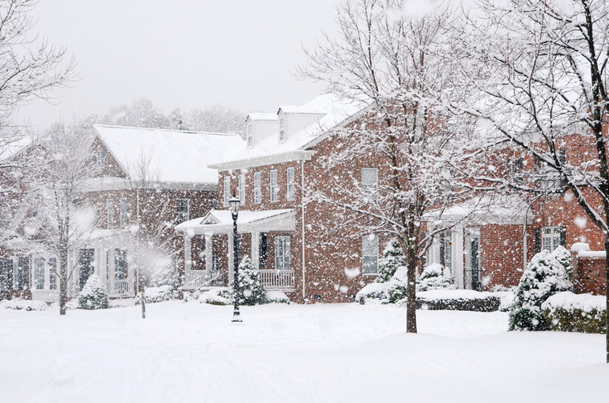 Street view of row of brick homes during snowstorm.