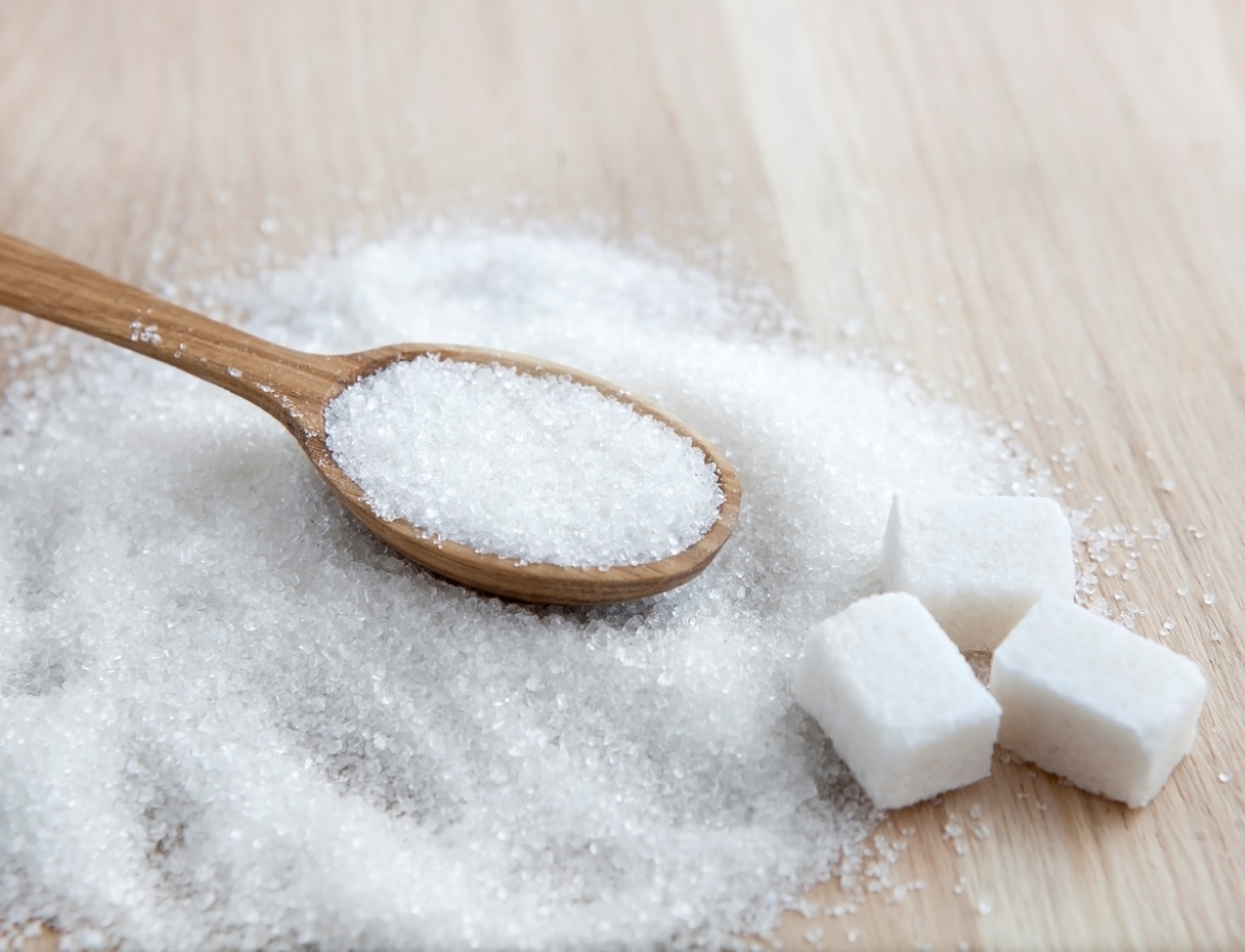 Sugar on table with wooden spoon.