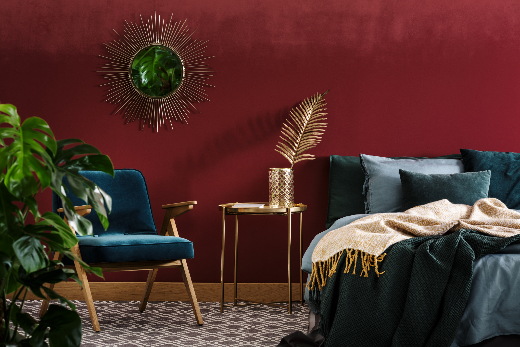 Bedroom with red walls and jewel-toned bedding and accent chair.