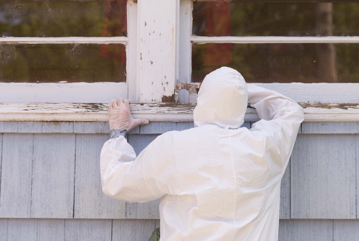 Professional in white suit removing lead based paint.