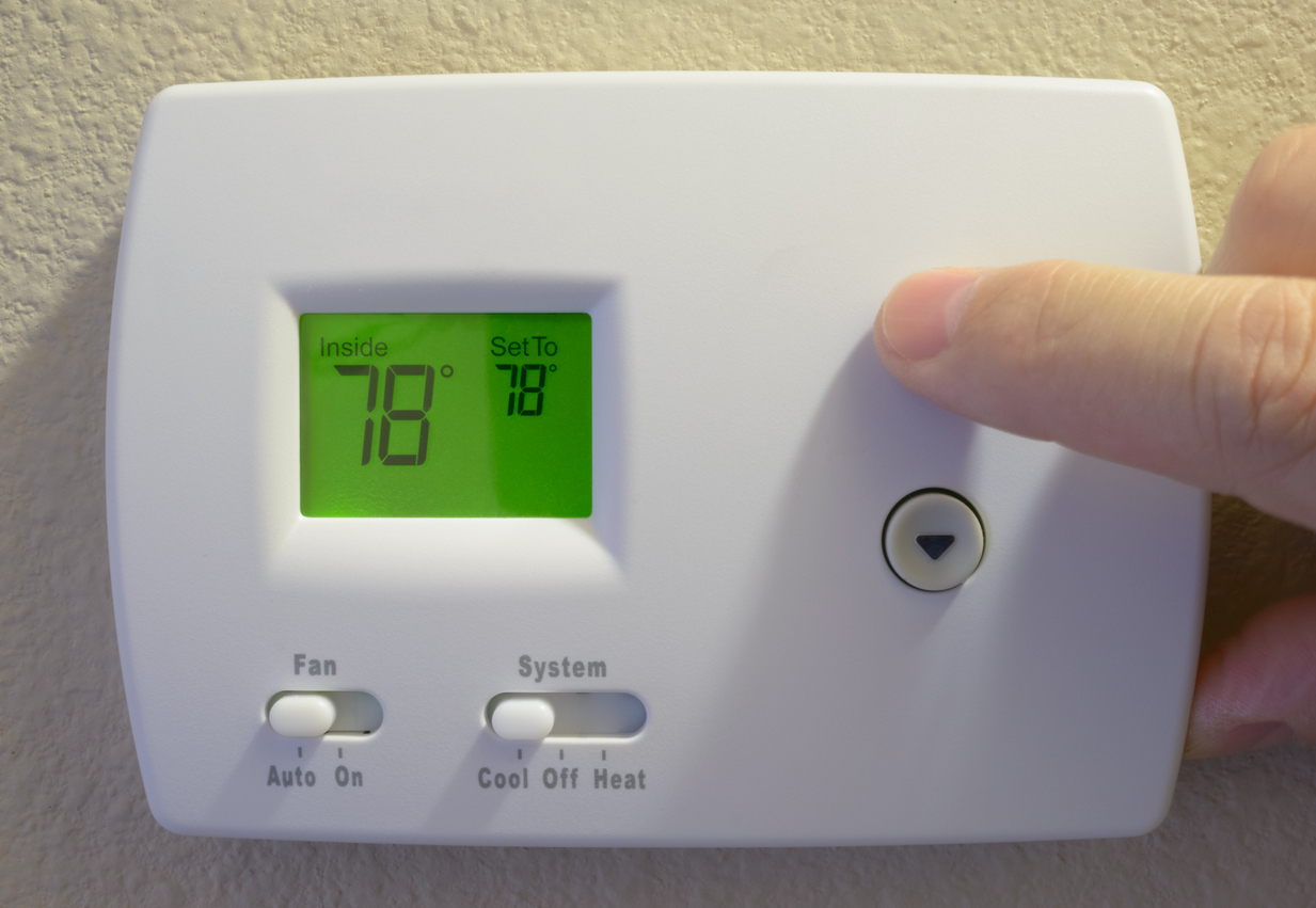 Person setting a digital thermostat to 78 degrees Fahrenheit.