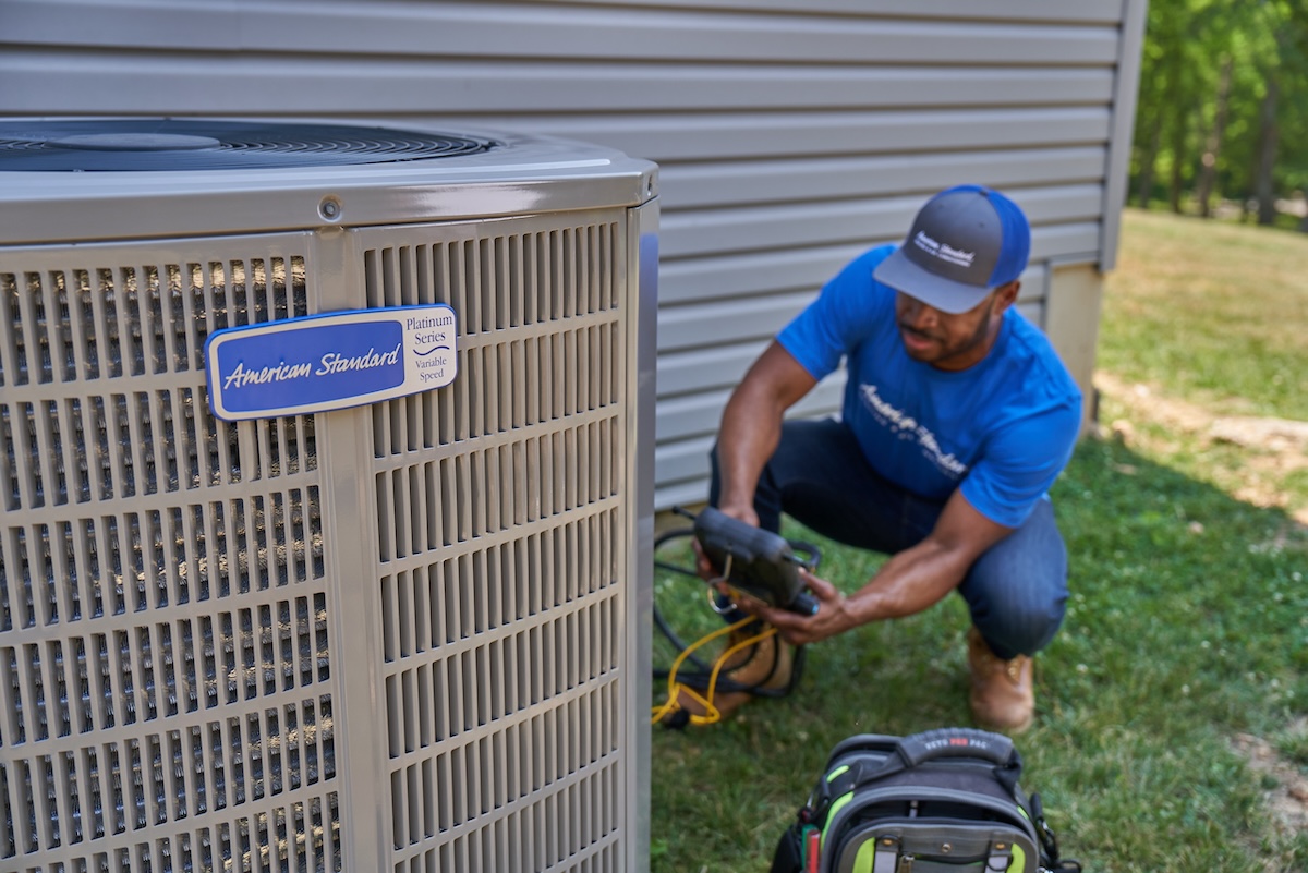 An American Standard HVAC technician installing a residential heat pump.