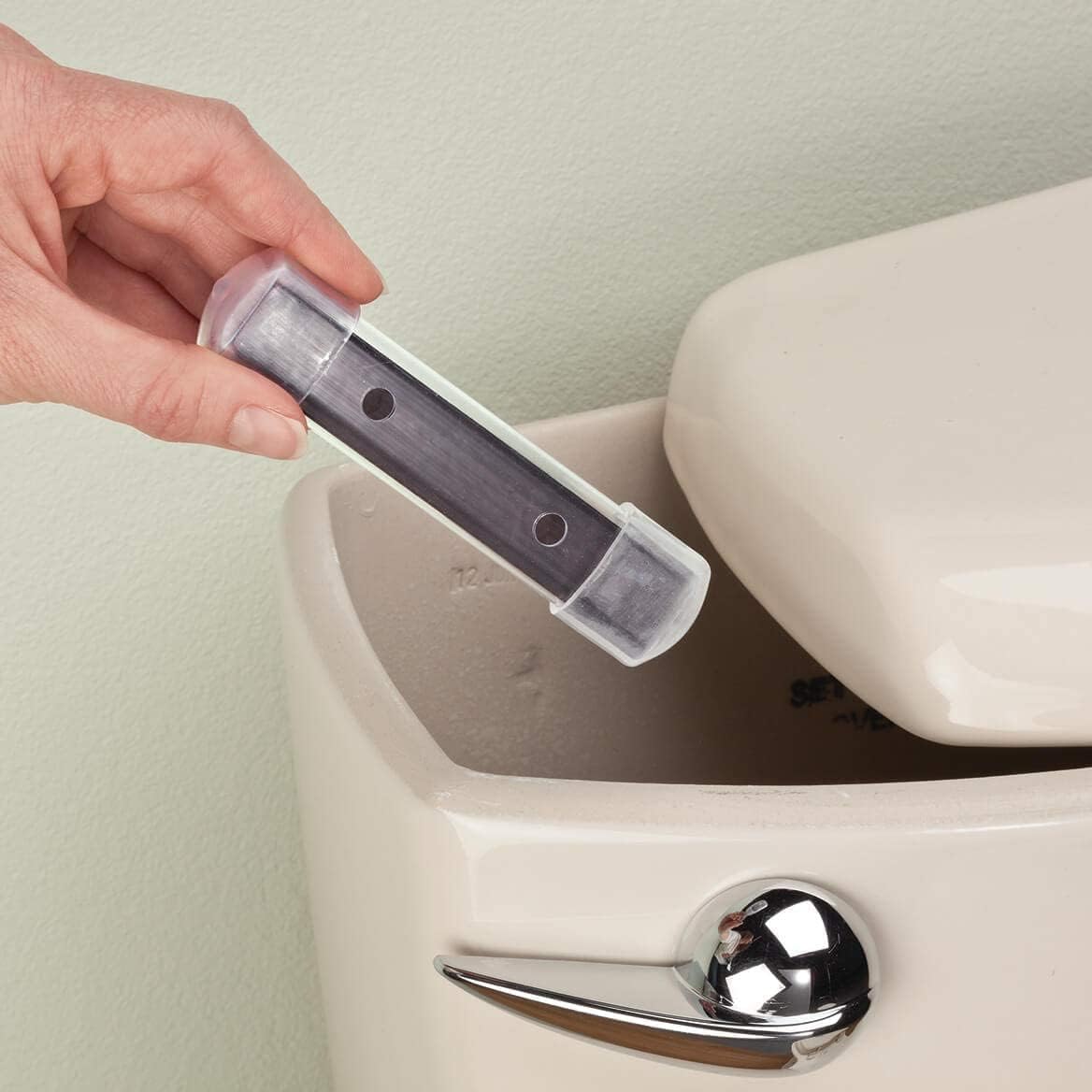 A hand drops a Bandwagon-Inc-Toilet-Cleaning-Magnet into a toilet tank.
