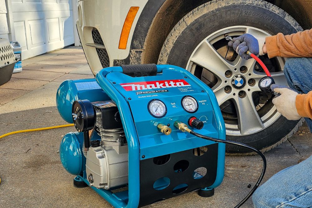 A person using the Makita MAC2400 2.5 HP Air Compressor to inflate a car tire.