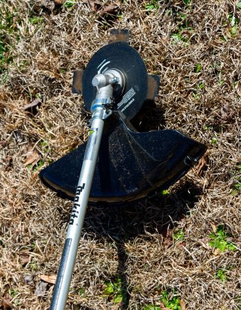 The cutting head on the Makita cordless brush cutter trimming grass and weeds to a short height.