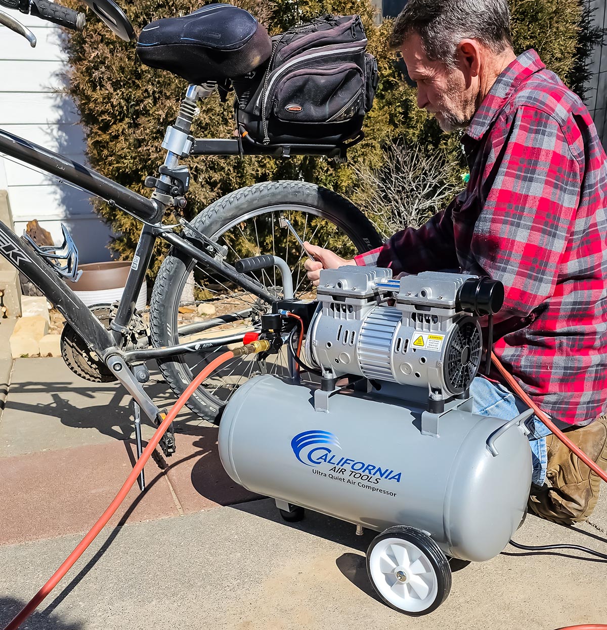 A person using the California Air Tools 8010 air compressor to inflate bike tires during testing.