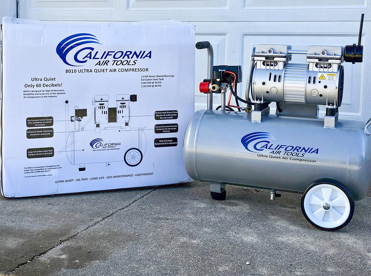 The California Air Tools 8010 Ultra Quiet Air Compressor on a driveway next to its box before testing.