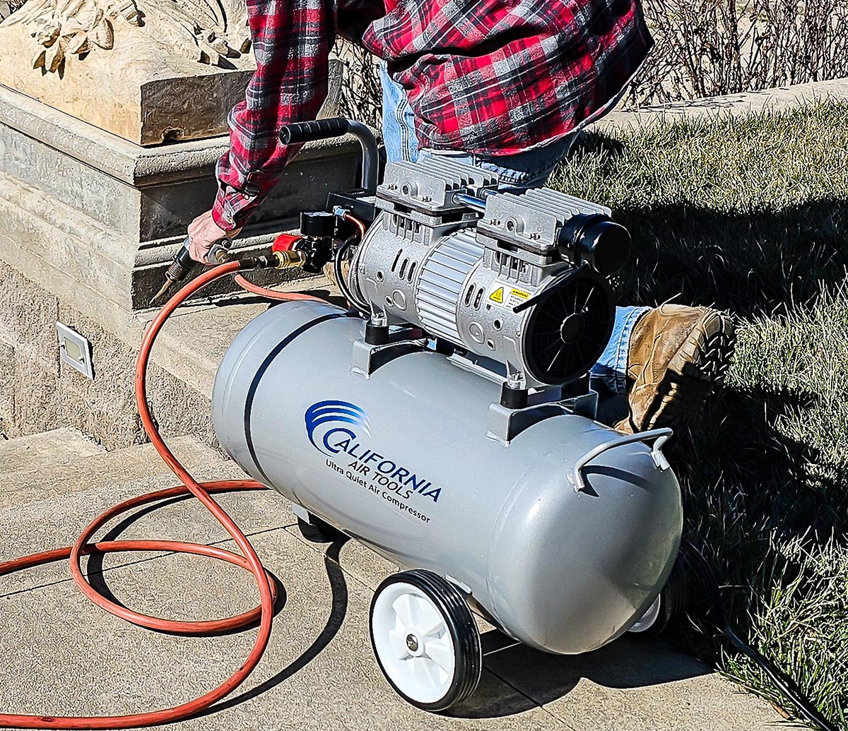 A person using the California Air Tools 8010 Ultra Quiet Air Compressor with a power tool during testing.