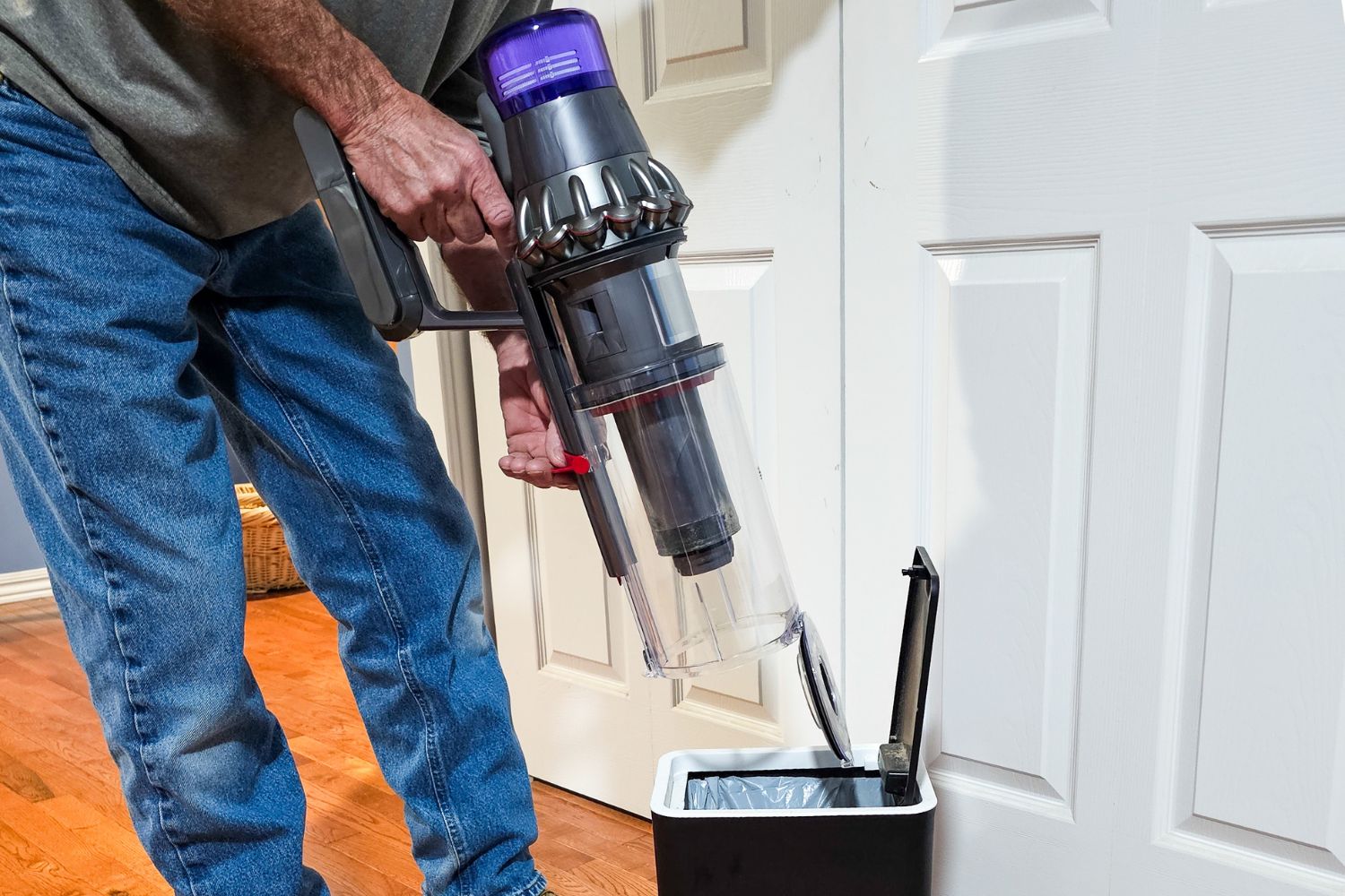 A person emptying the Dyson Outsize cordless vacuum dustbin into a small trash can.