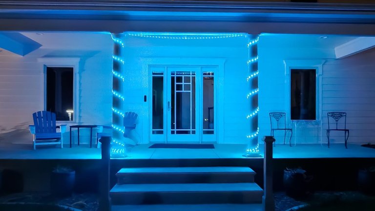 Blue LED strip lights wrapped around white columns on front porch