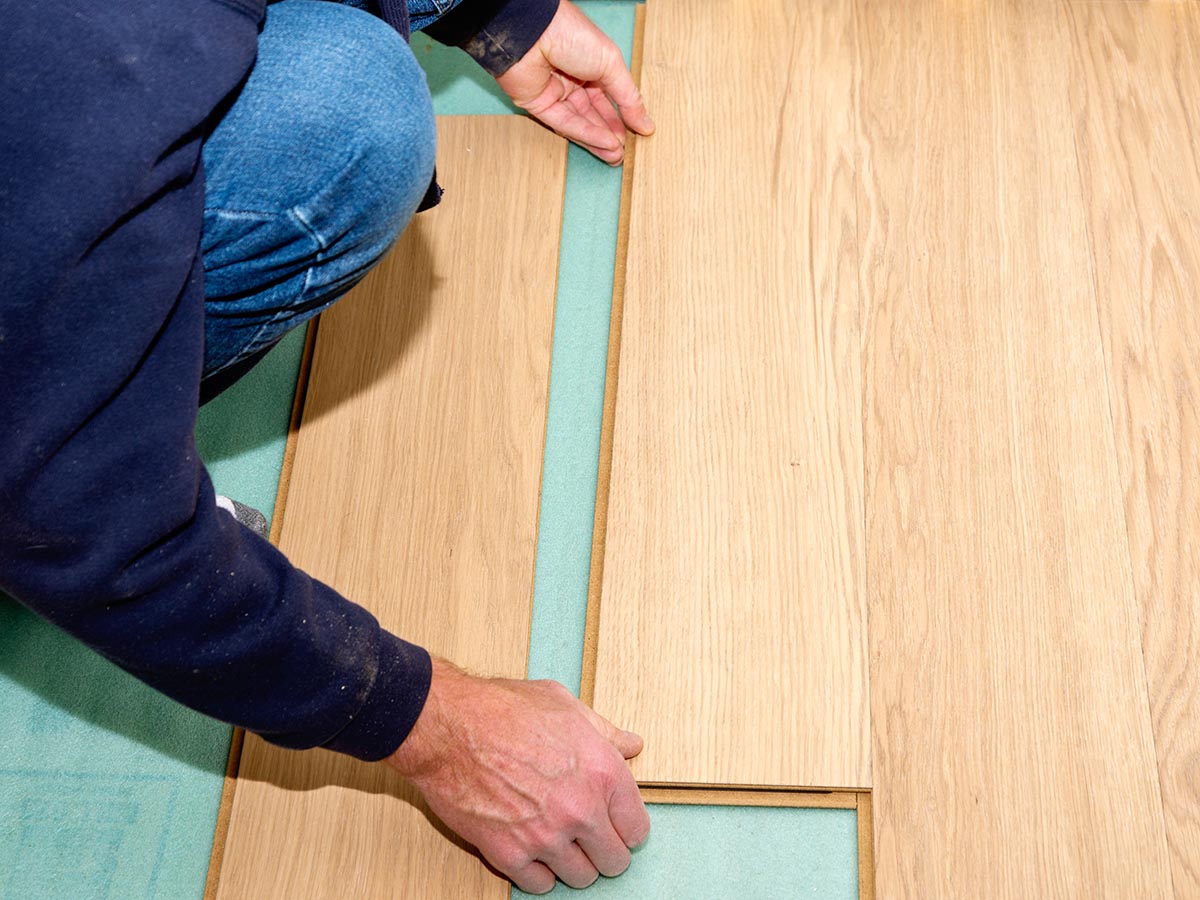 A person installing Flooret flooring using their click-lock system.