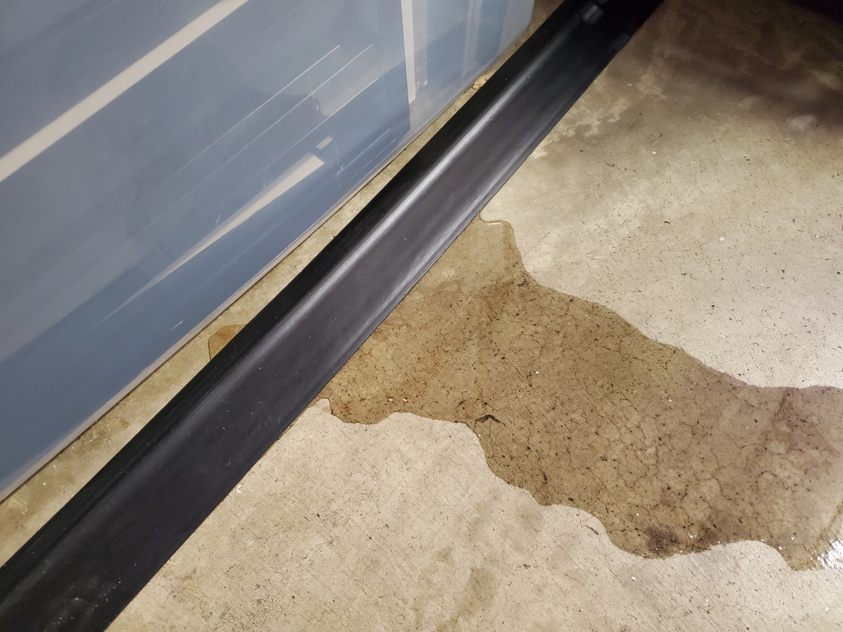 A close up of a water leak seeping from the floor.