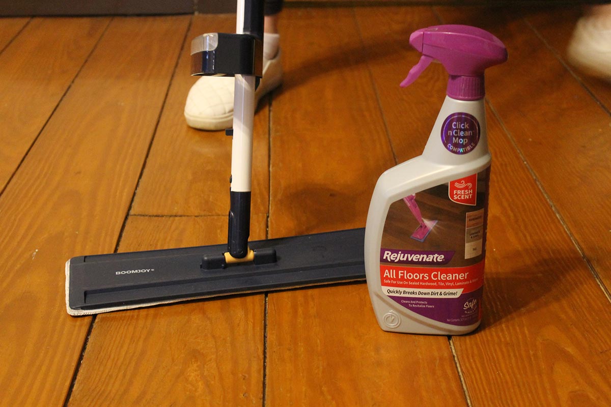 The Rejuvenate All Floors Cleaner next to a mop during testing to clean a wood floor.