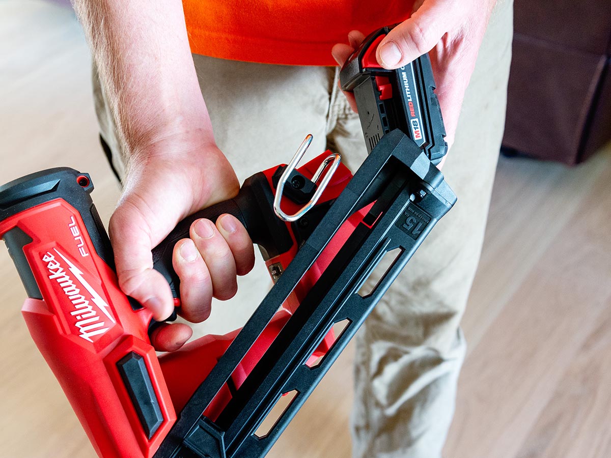 A person removing the rechargeable batter from the Milwaukee 15-Gauge Finish Nailer.